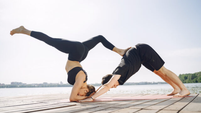 Man and woman doing yoga exercises by the water